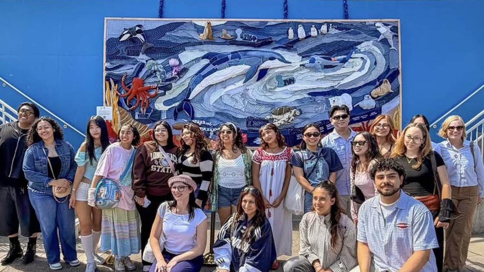 Group poses in front of SeaWorld mural