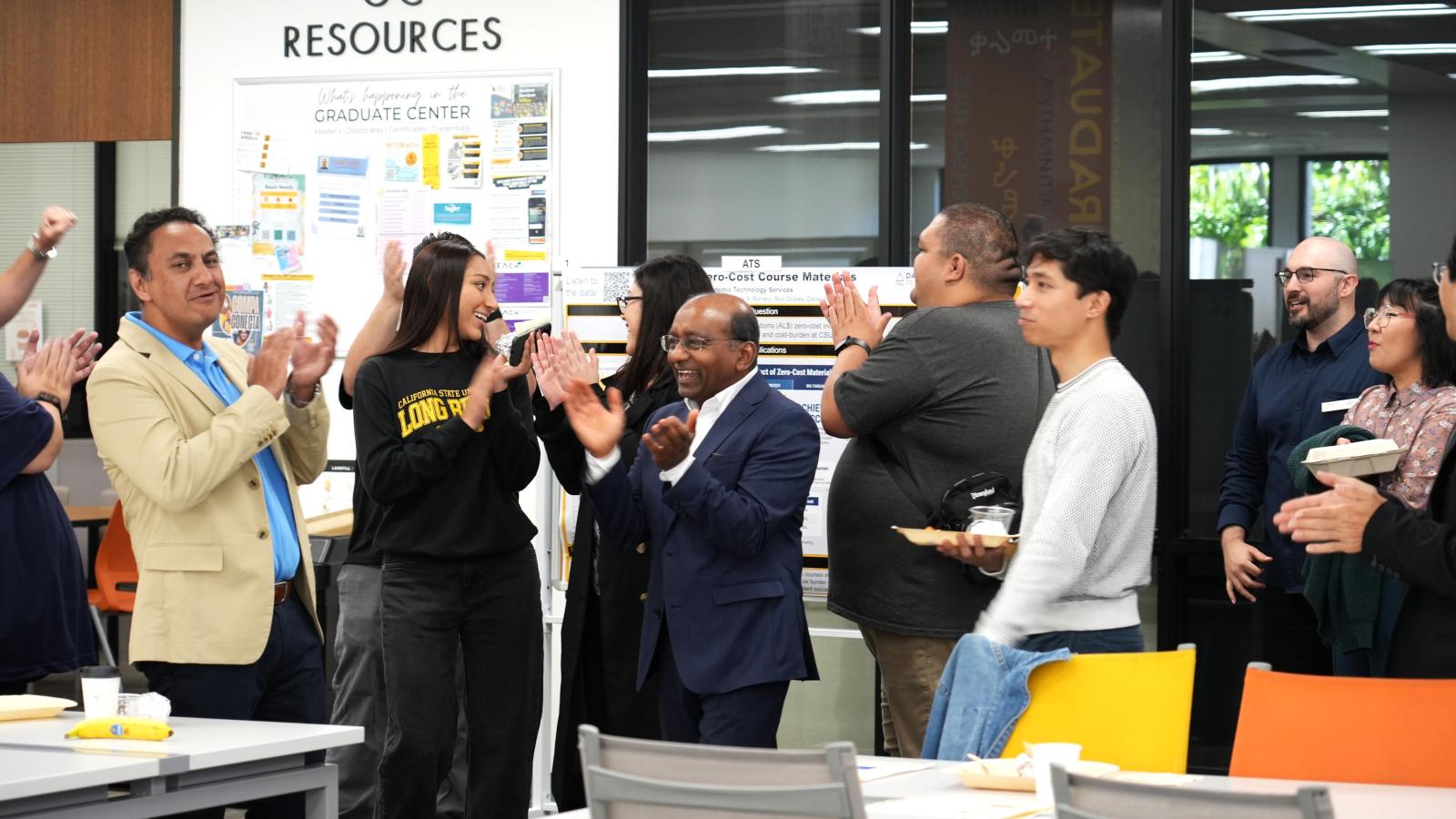 a group of students and staff clap their hands in celebration
