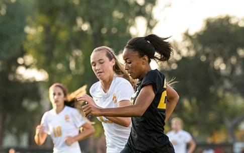 Two soccer players battle for possession of ball