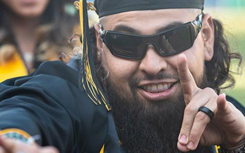 Male graduate wearing sunglasses gestures during Commencement