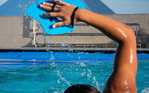 Student swimming with hand paddle