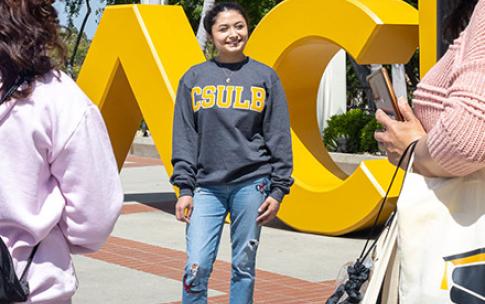 Student stands in front of BEACH sign