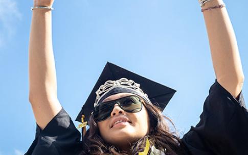 Graduate raises her arms in air