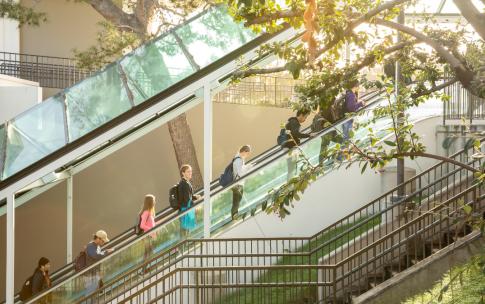 students riding up escalator