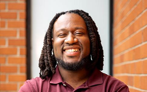 Joshua James, a recipient of the Black Alumni Scholarship, smiling with arms crossed