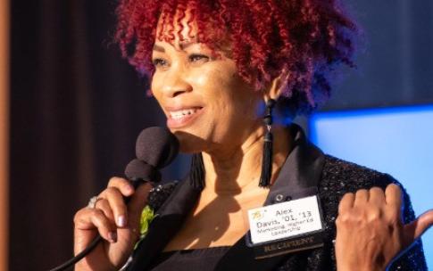 2025 Distinguised Alumni honoree Adriene “Alex” Davis speaking with a microphone in hand