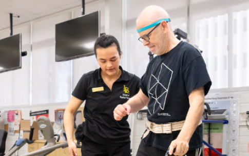 Romina Silva helps a Neuro Lab client as he uses a cane to walk