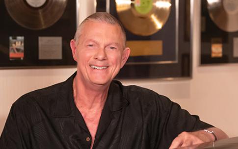 Richard Carpenter at piano, gold records behind him