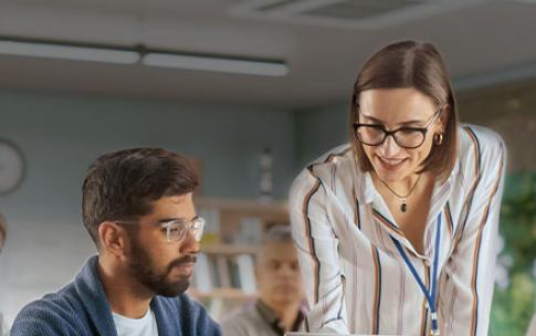 Woman teaching male student with laptop