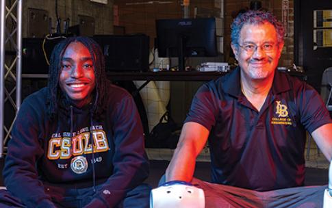 Two people sit side by side with a robot in a the foreground