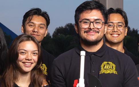 A person holds a model car alongside three others, all in matching shirts