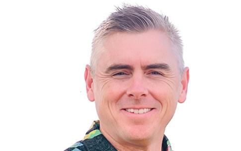 Man stands in front of white background in colorful shirt