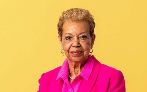 Person wearing pink faces camera with yellow background