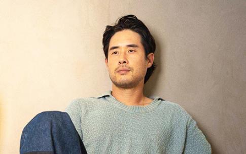 Actor Raymond Lee '08 sits on the floor with a CSULB mug in his hand