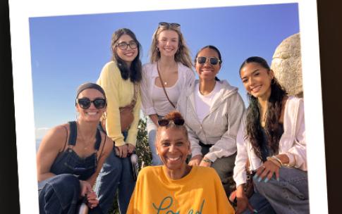 A group of people pose together outdoors on a rocky hillside