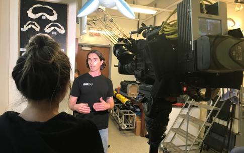 Postdoctoral student James Anderson speaks to a broadcast photojournalist,