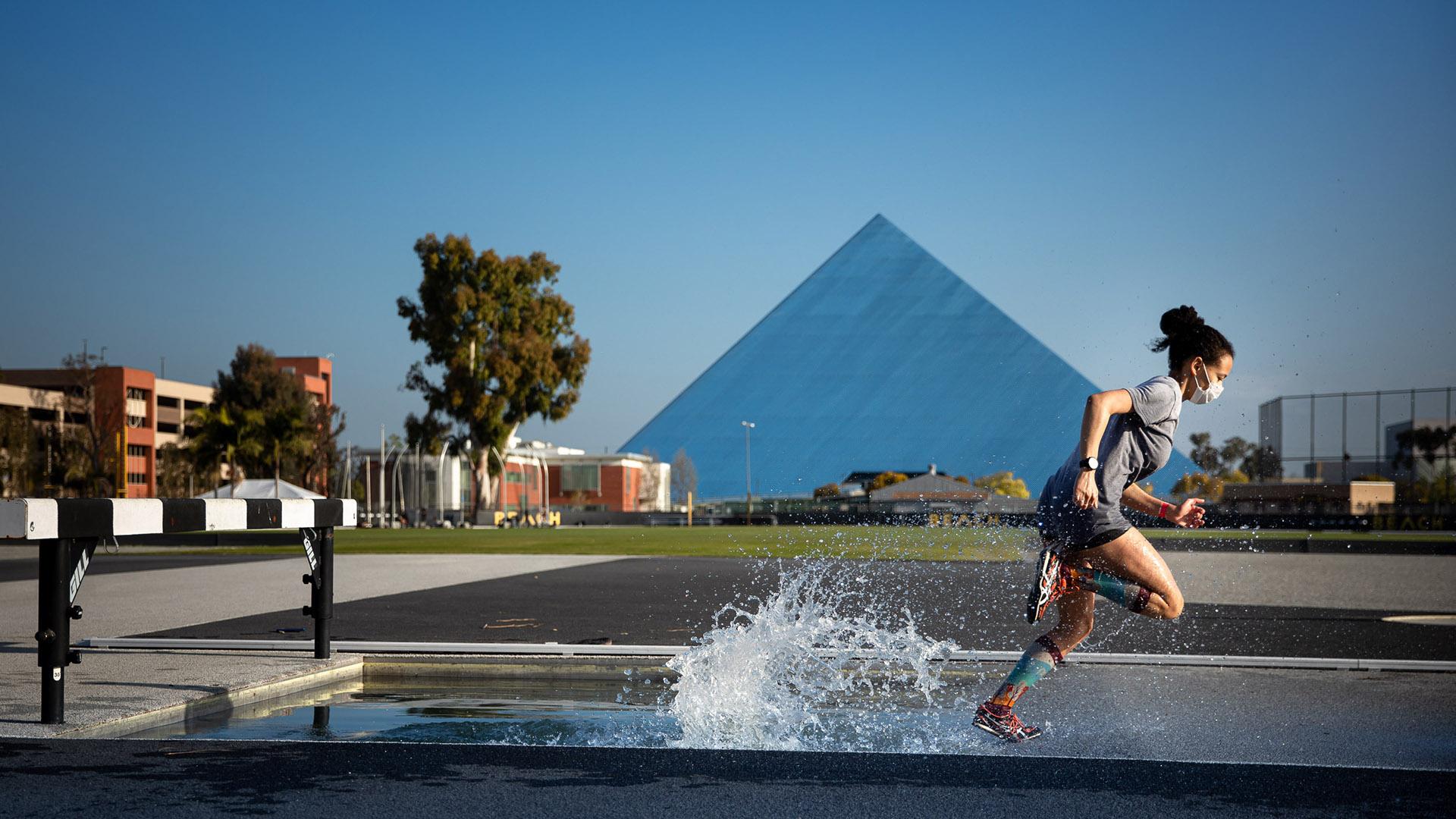 Runner creates splash running in Steeple chase with Pyramid in background