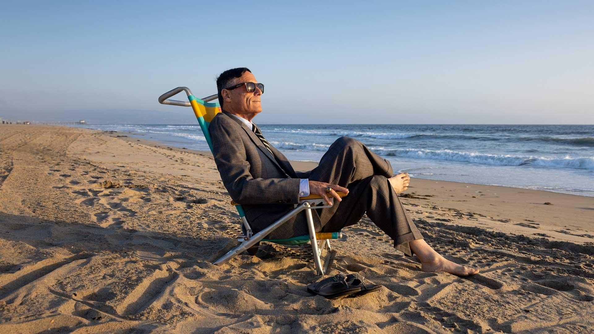 Alumnus Wayne Powell sits in a chair at the beach