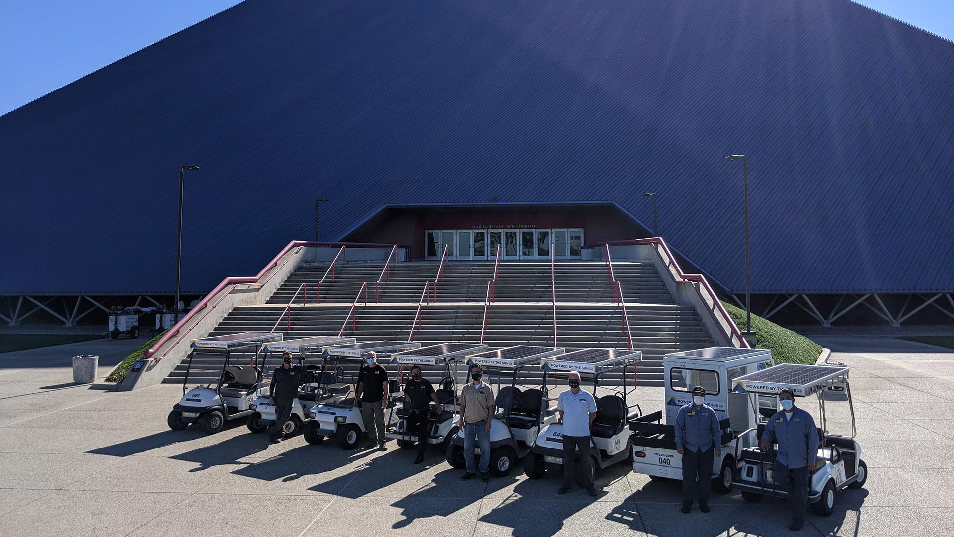 Workers stand beside solar-powered golf carts