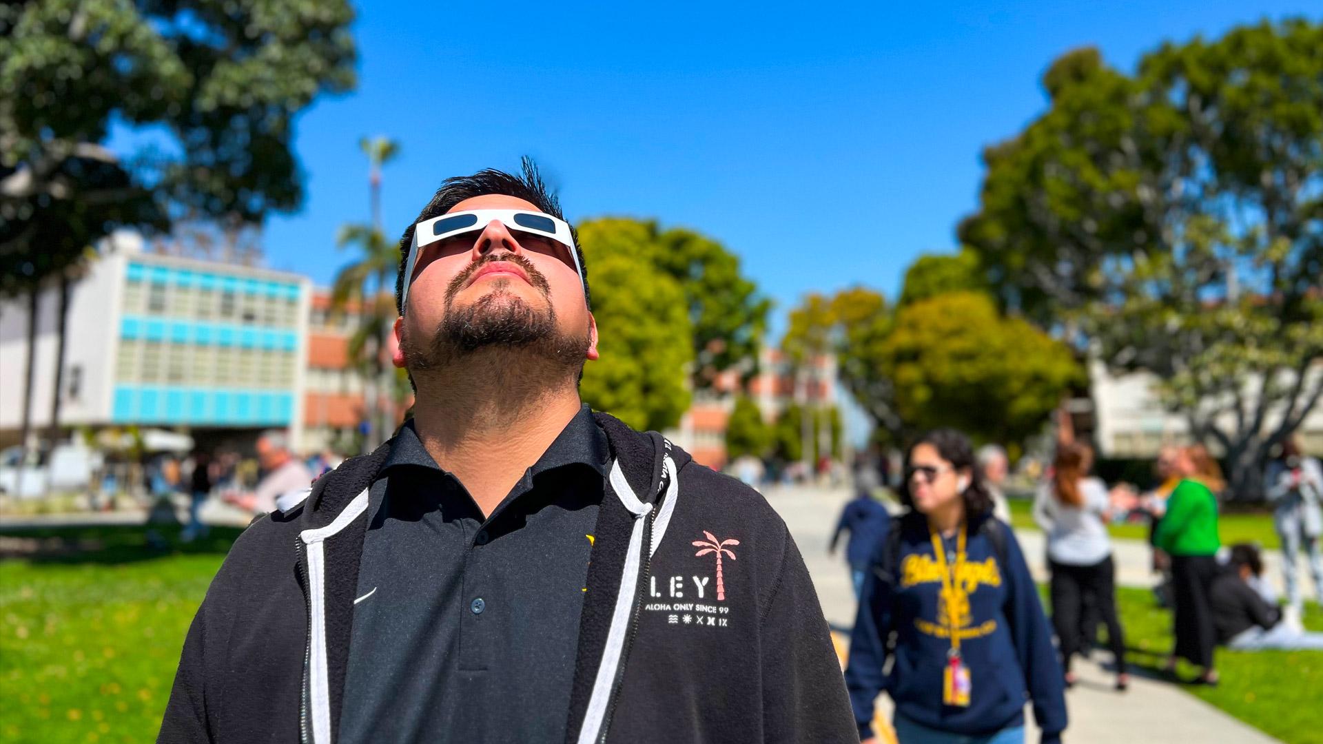 Man gazes at sky on CSULB campus during the partial solar eclipse