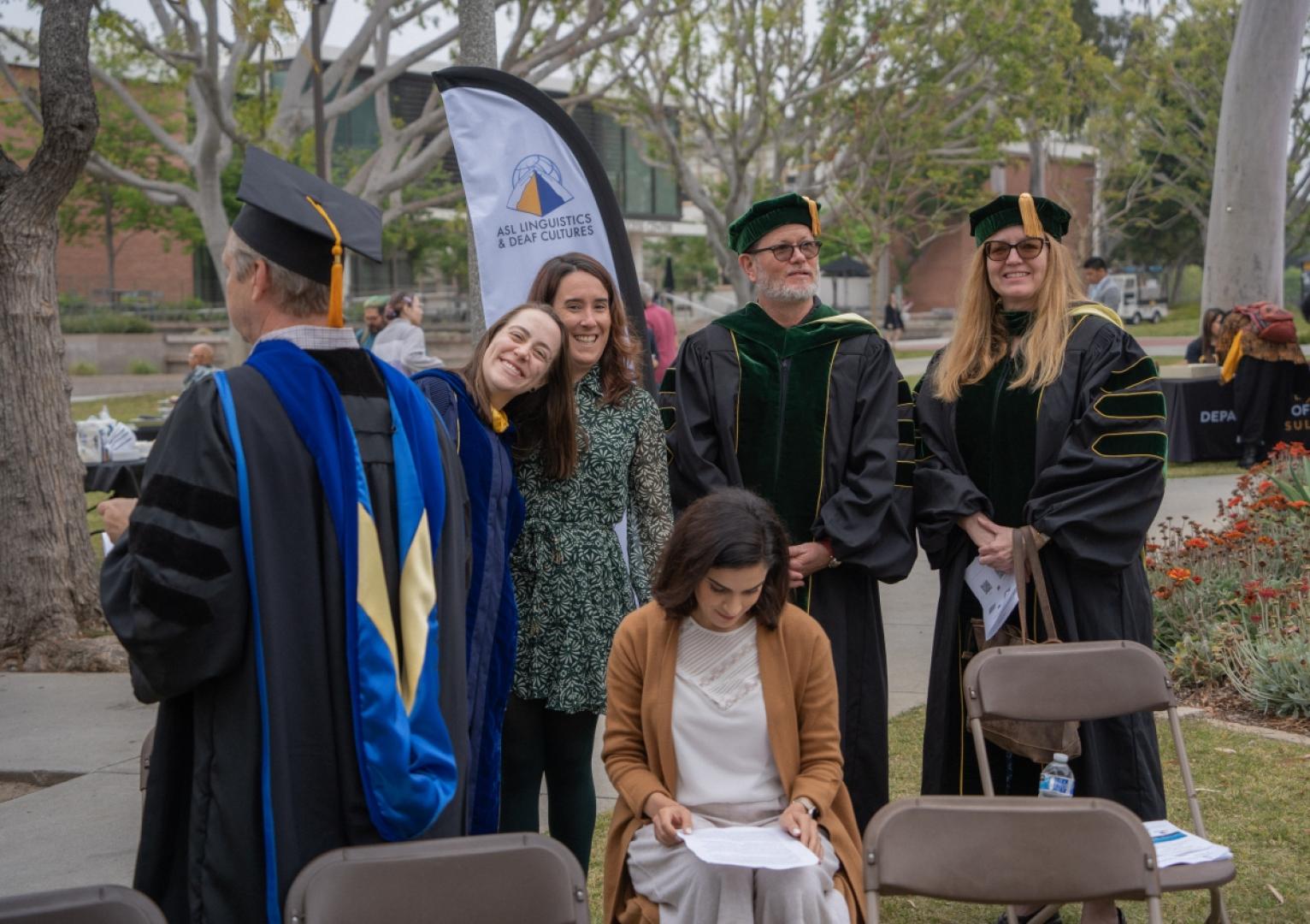 Group stands smiling at grad ceremony.
