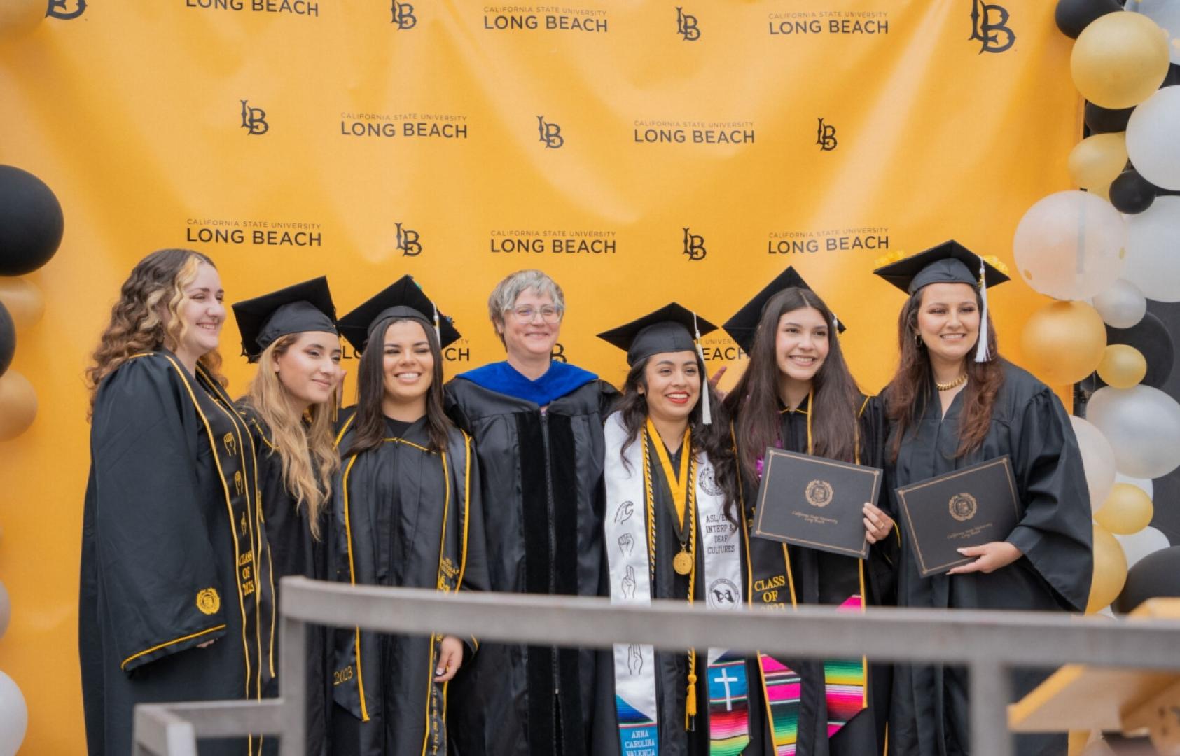 Group of students and faculty smiling at grad ceremony.