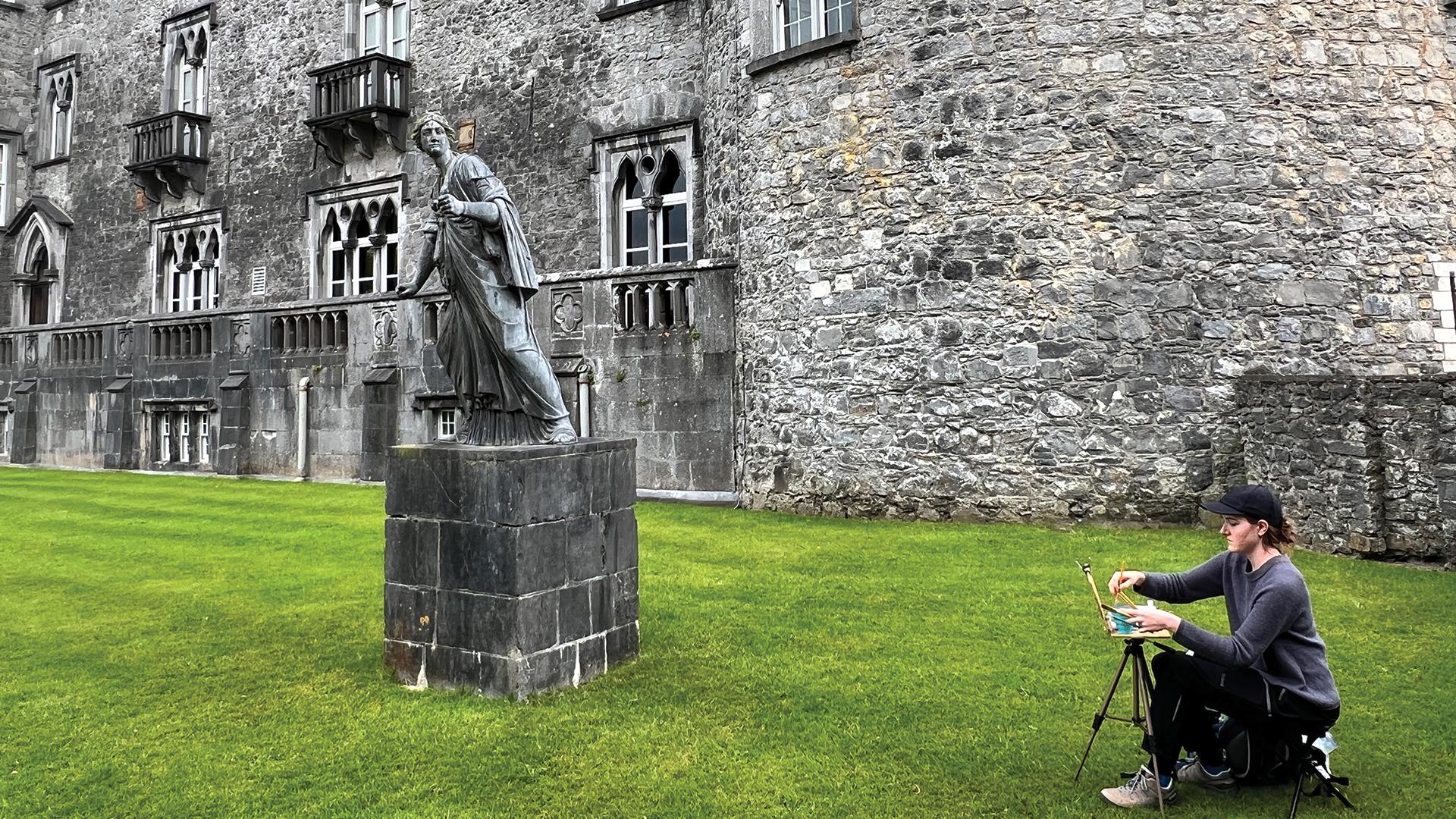 A student painting near a statue