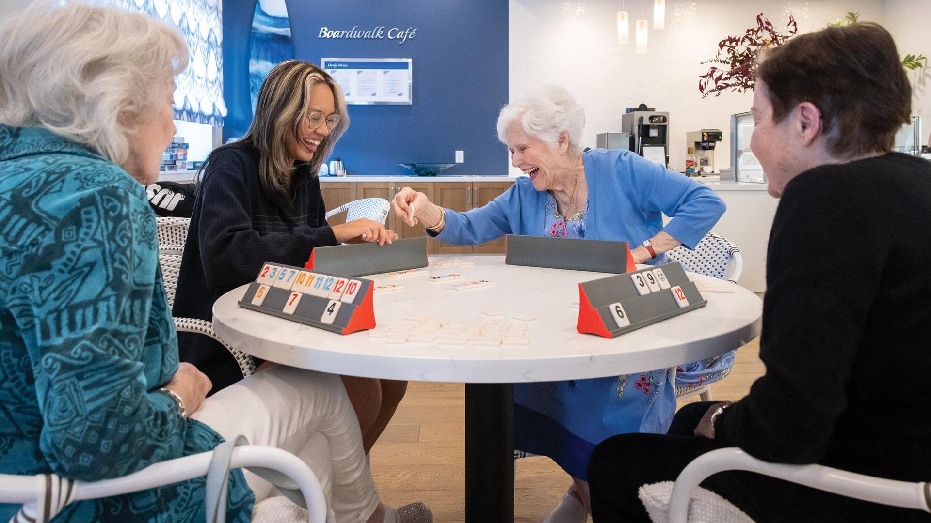 A senior laughs along with a student at a gaming table