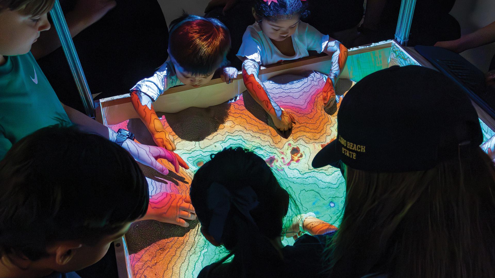 Silhouettes of children playing in augmented reality sandbox