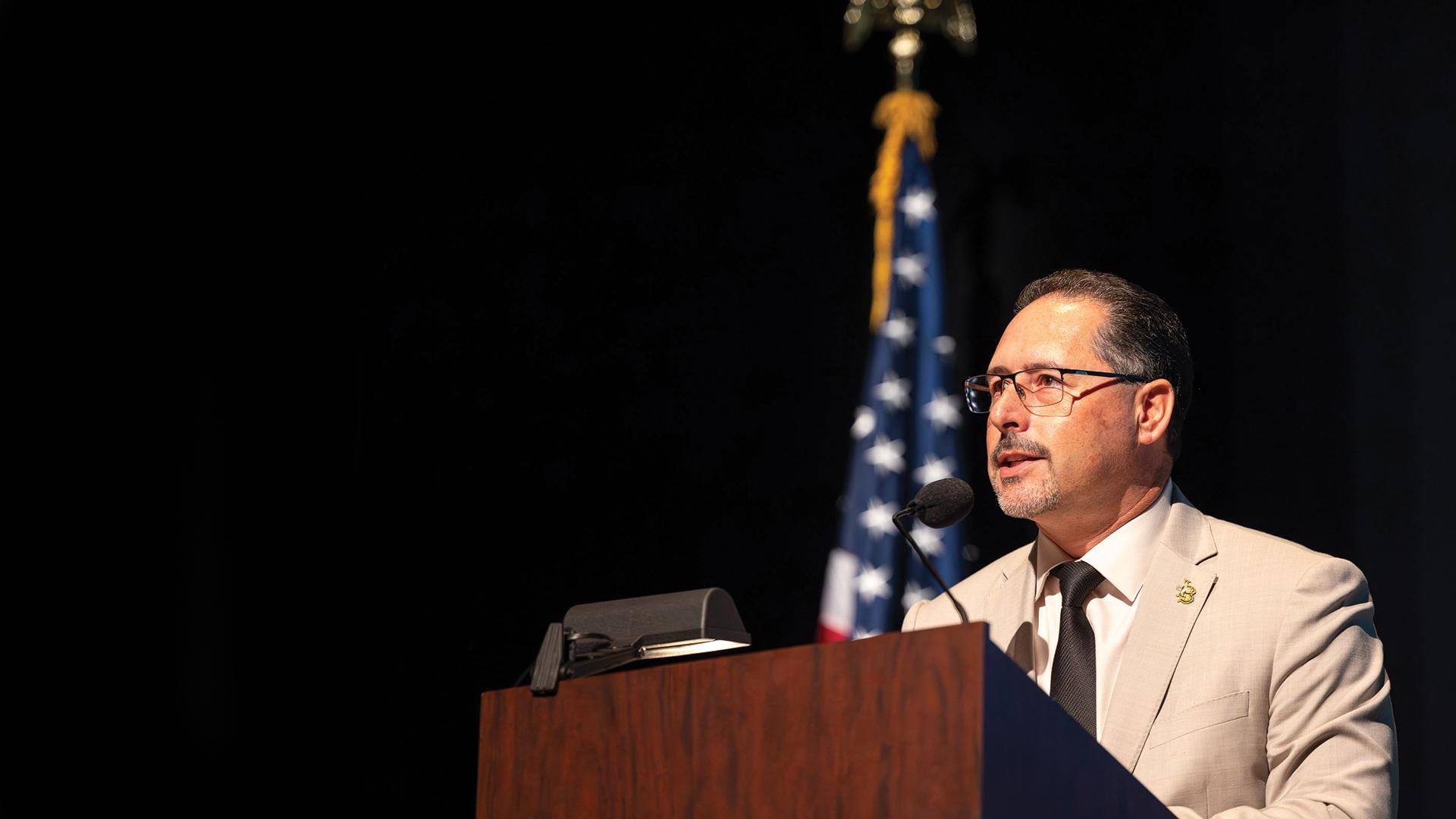 Vice President Dan Montoya speaks in front of an American flag