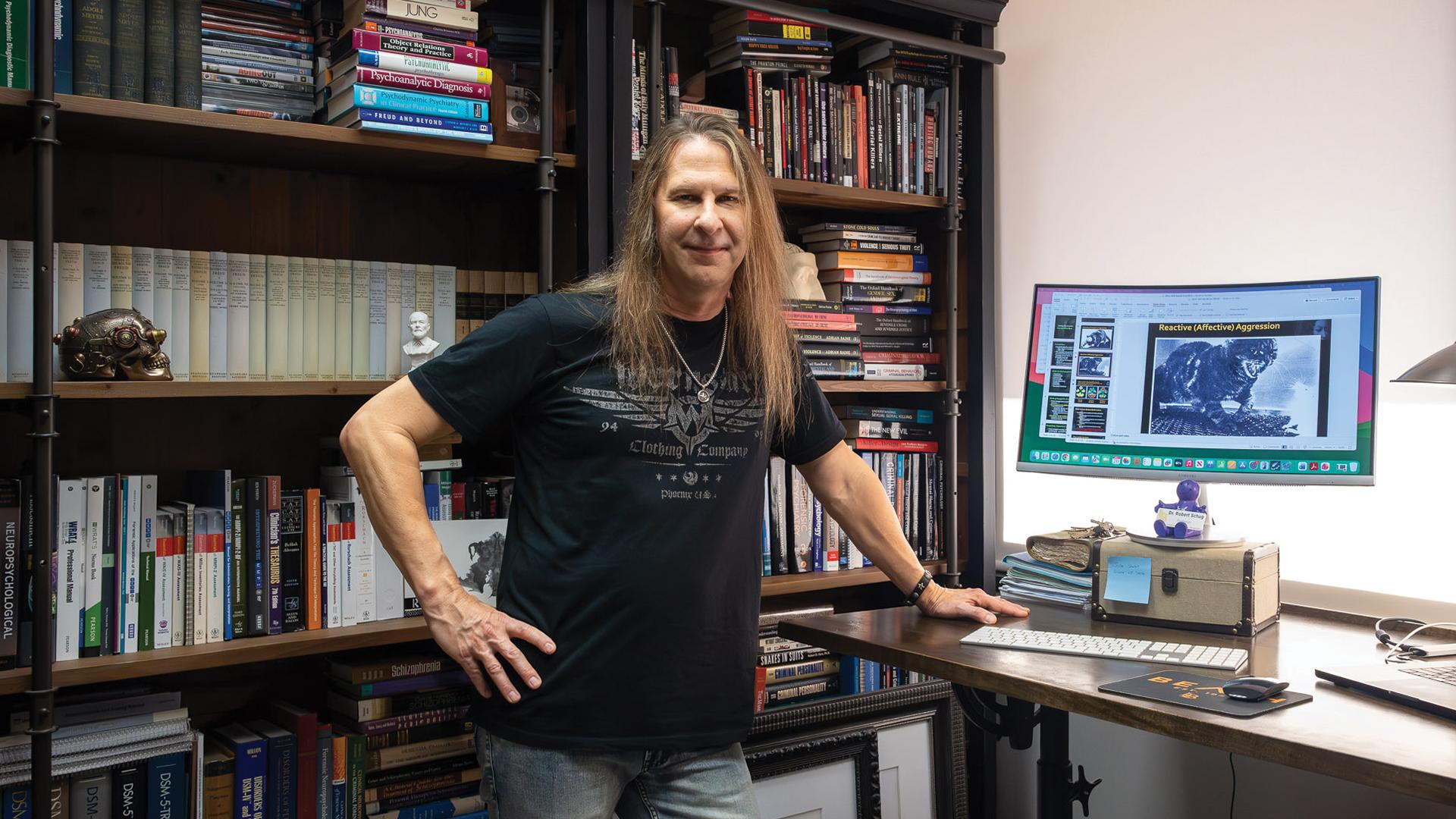 A person with long hair stands at a desk in an office