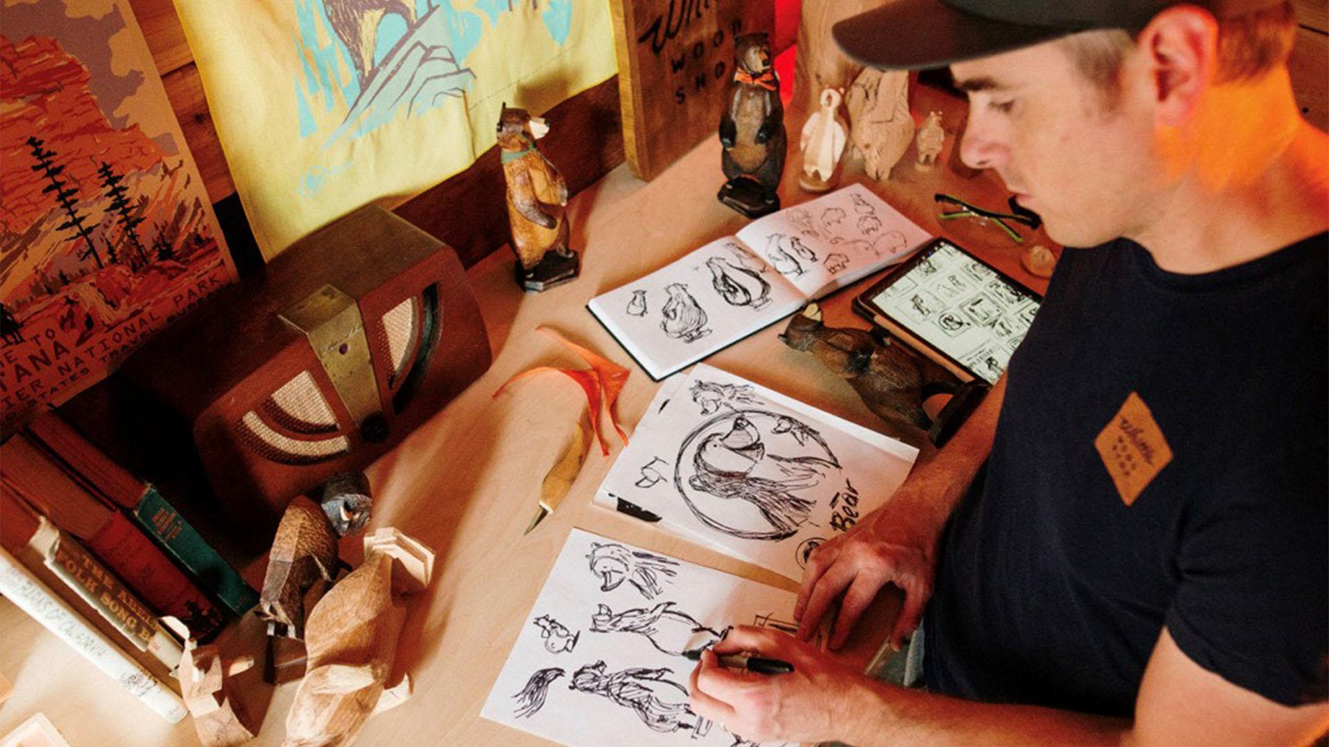 A person stands over a desk drawing cartoons characters