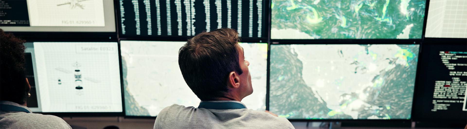 scientists monitoring multiple screens that contain weather data