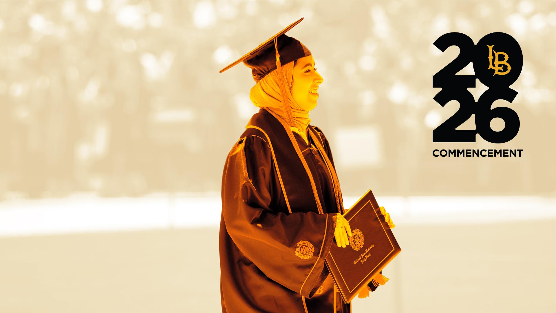 A graduate wearing regalia and holding a diploma