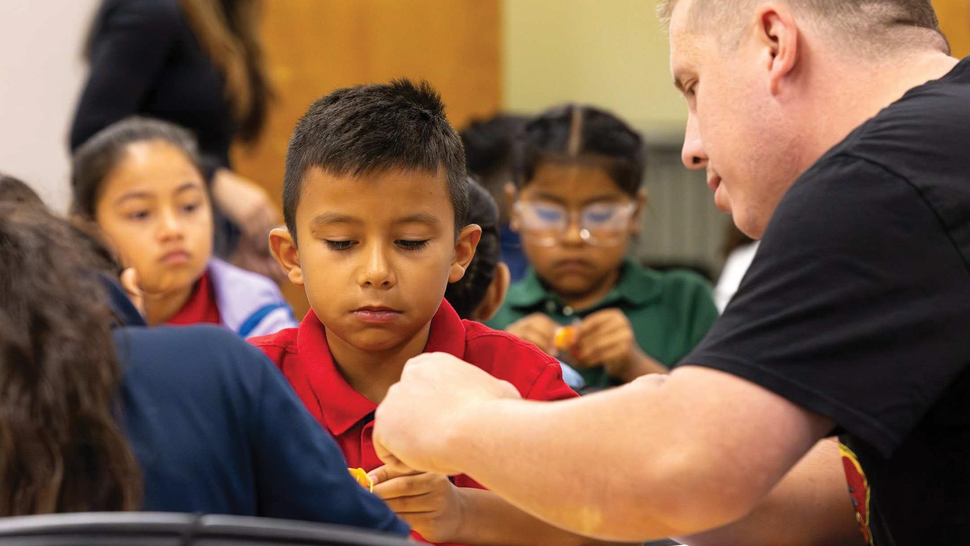 A CSULB student teacher, right, helps an elementary student build a robotic bug