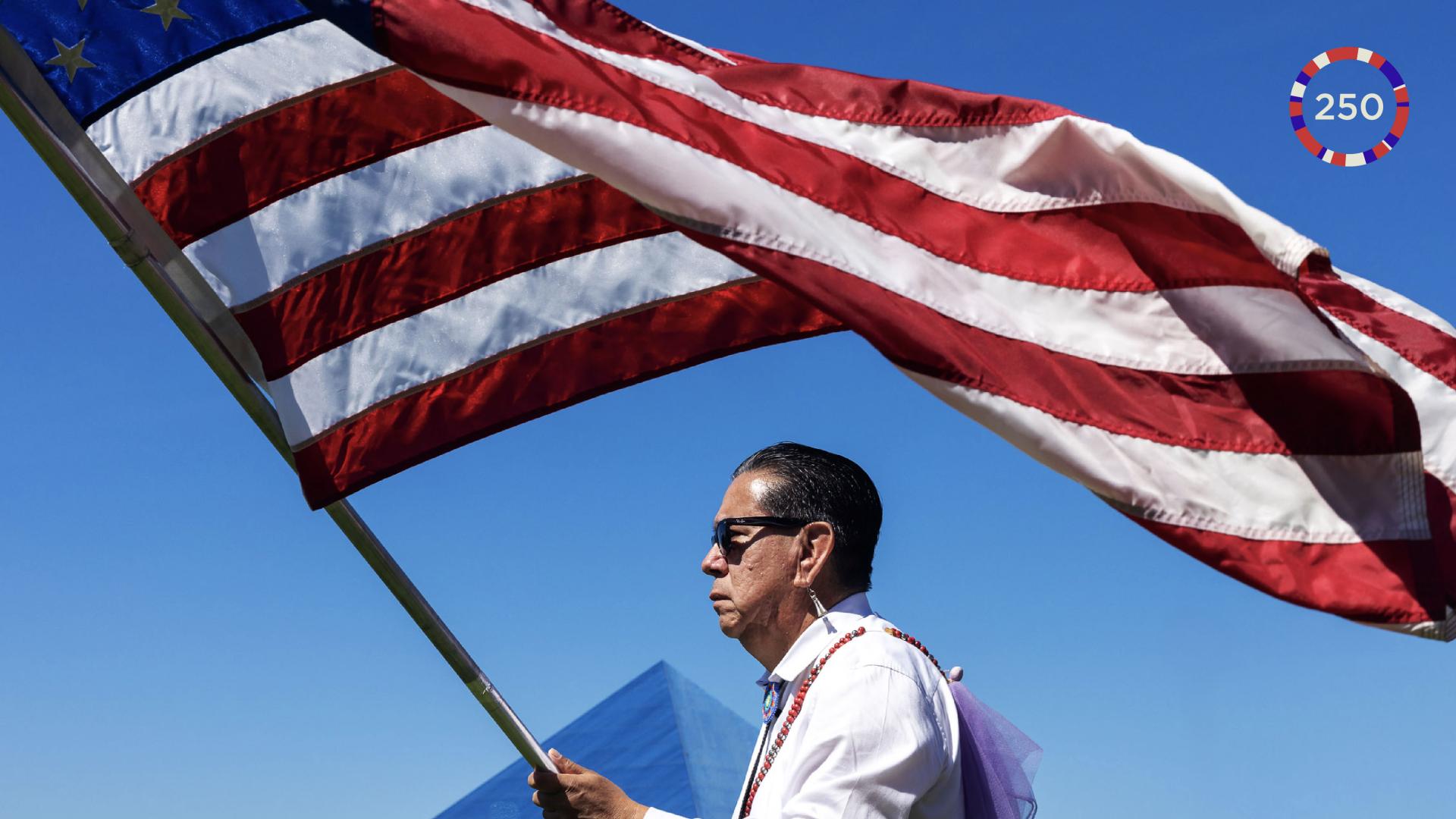 Native American man waving American flag with pyramid in background