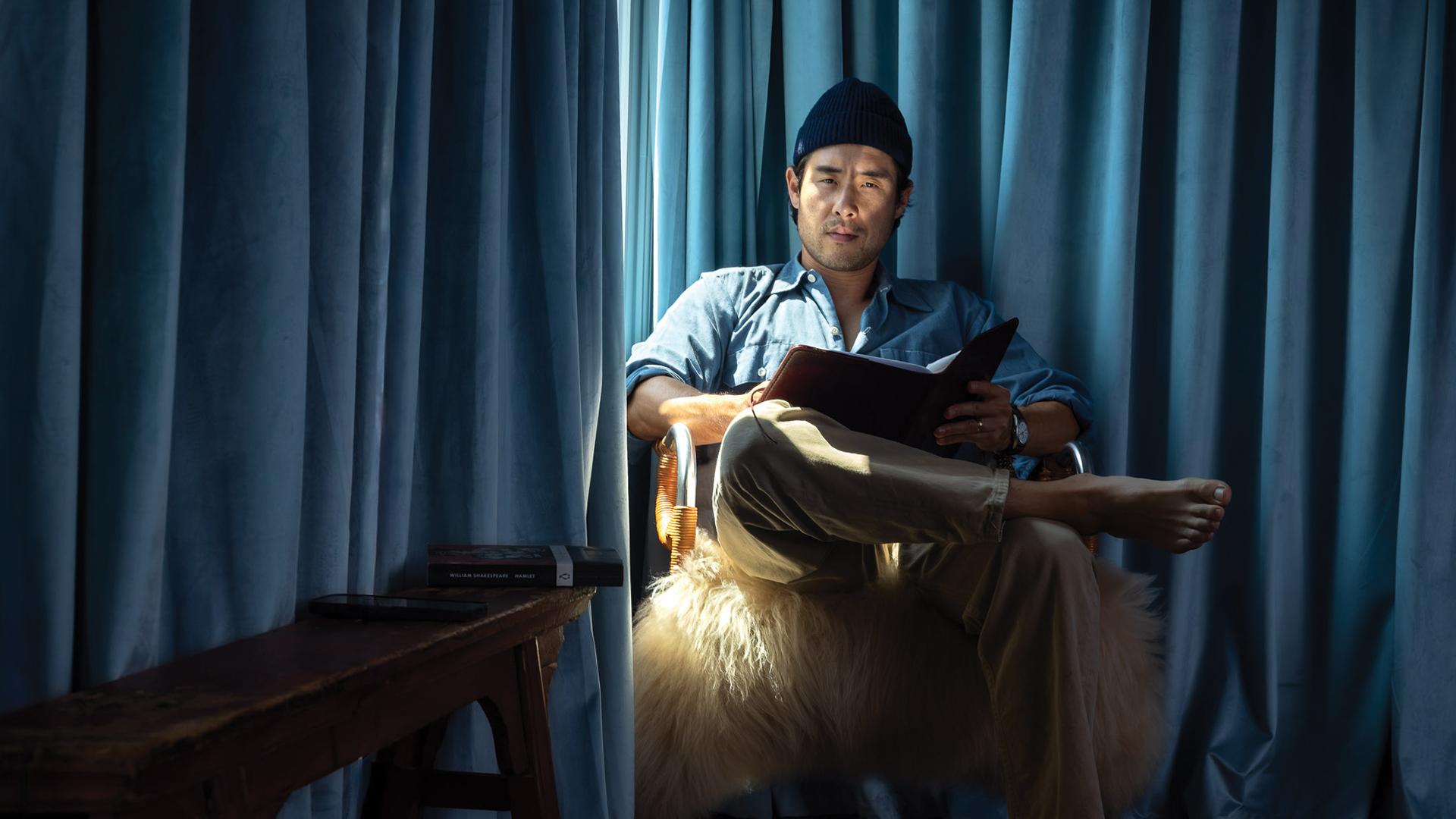 Raymond Lee '08 sits by the window with a script