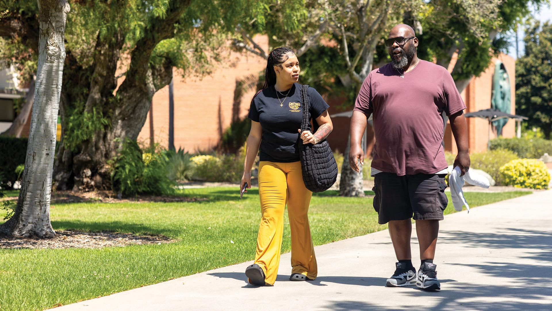 CSULB Guardian Scholar Heaven Mitchell walking with case manager Howard Channel