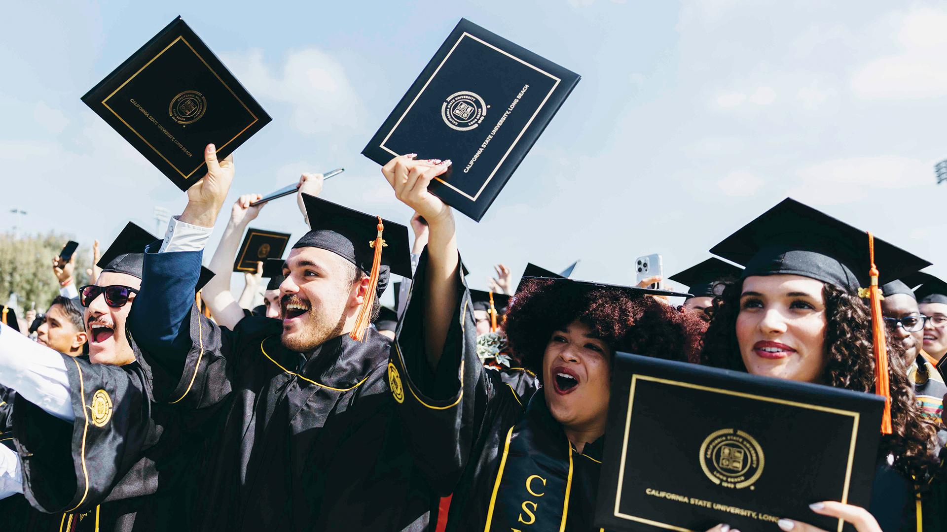 CSULB graduates holding up their diplomas at Commencement