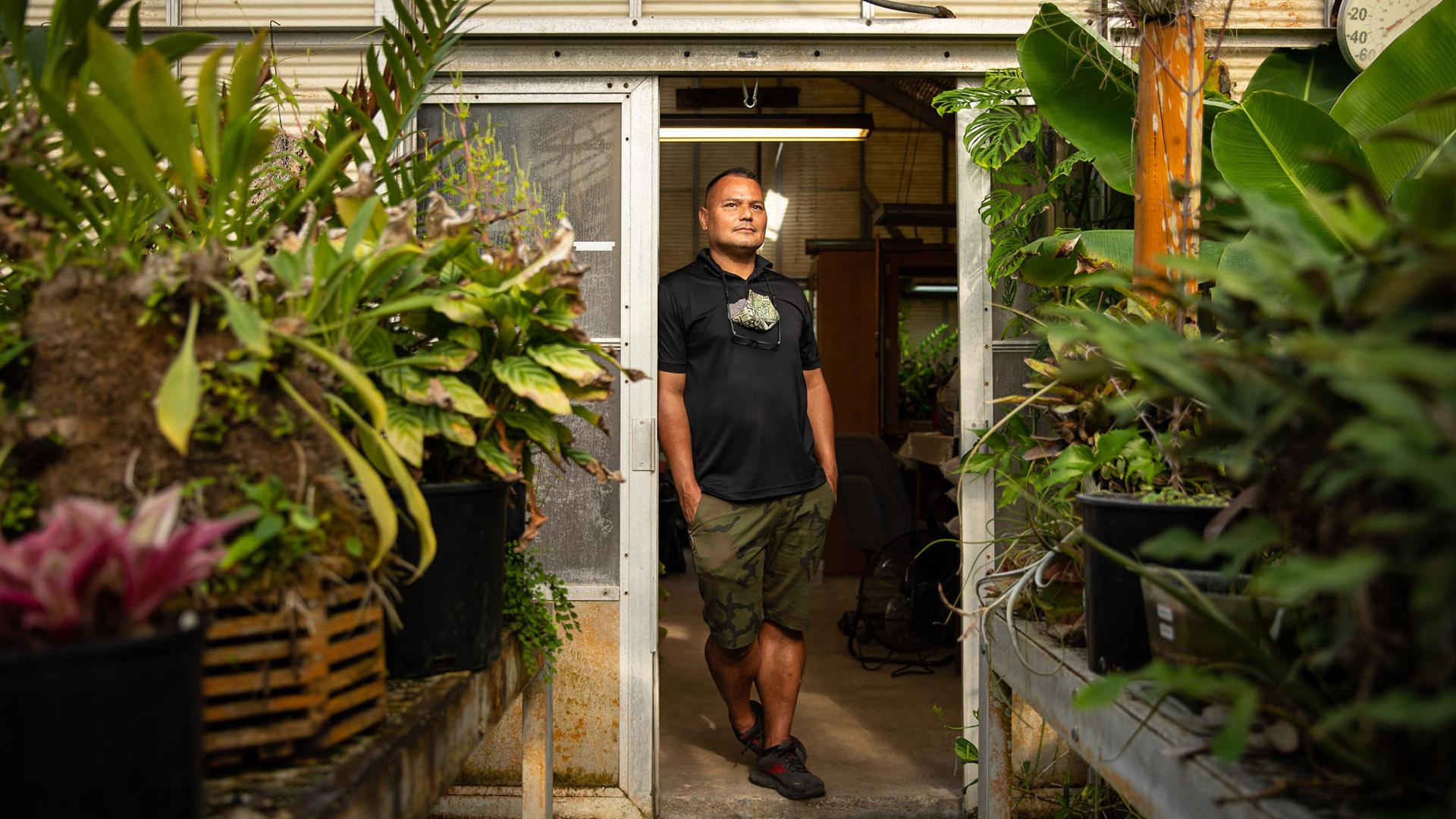 Botanist Brian Thorson standing by greenhouses