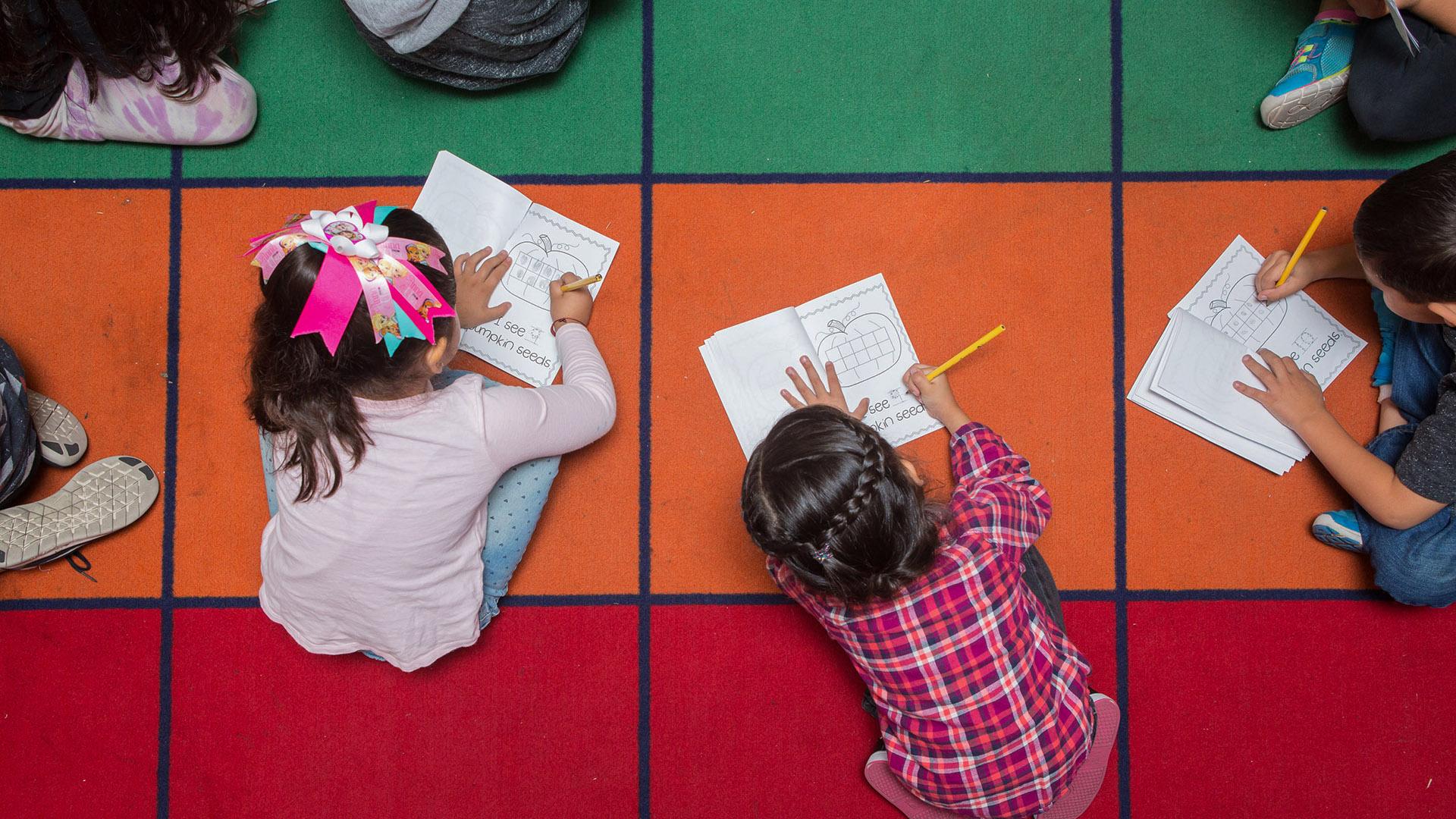 Kindergarden students working on the colorful classroom floor.