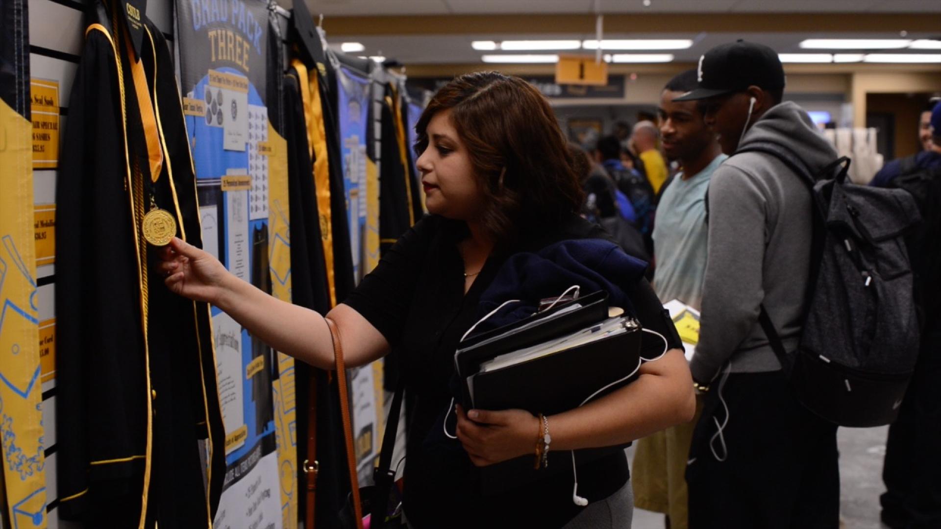 Students looking at caps and gowns.