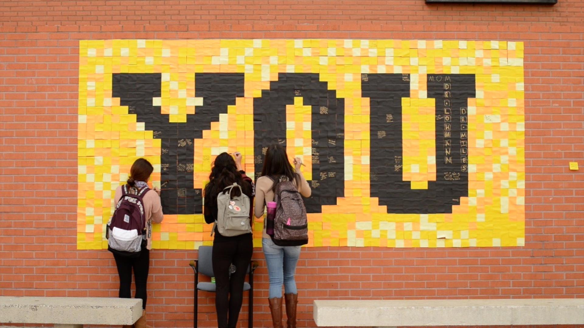 Students write messages on the Grateful Wall.
