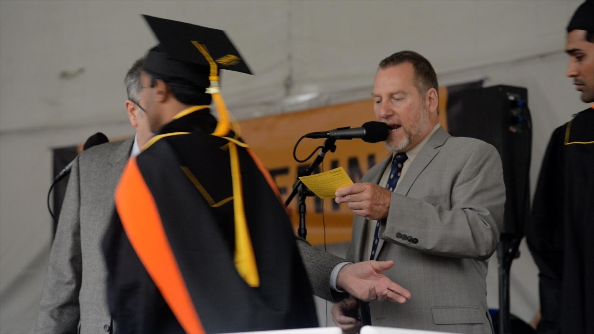 Jamieson Price reads a students name to crowd at commencement ceremony.