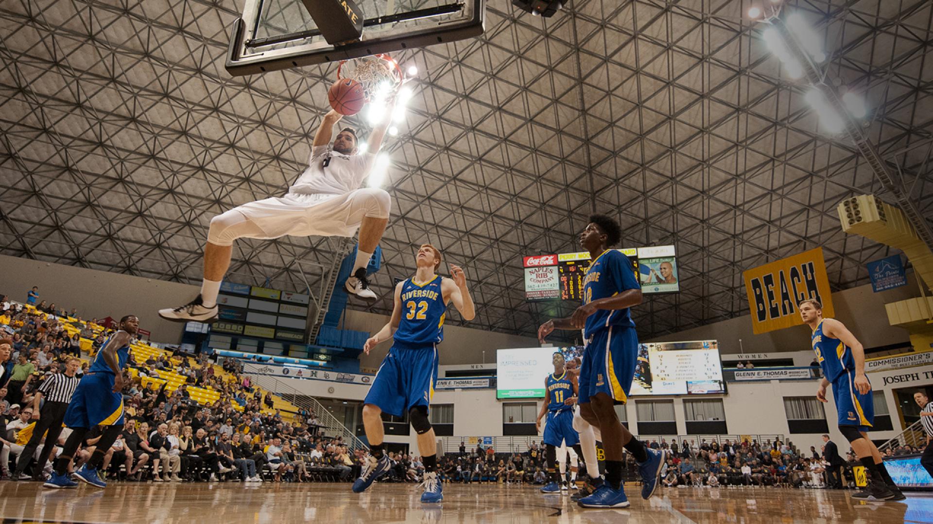 Basketball player slam dunks the ball.