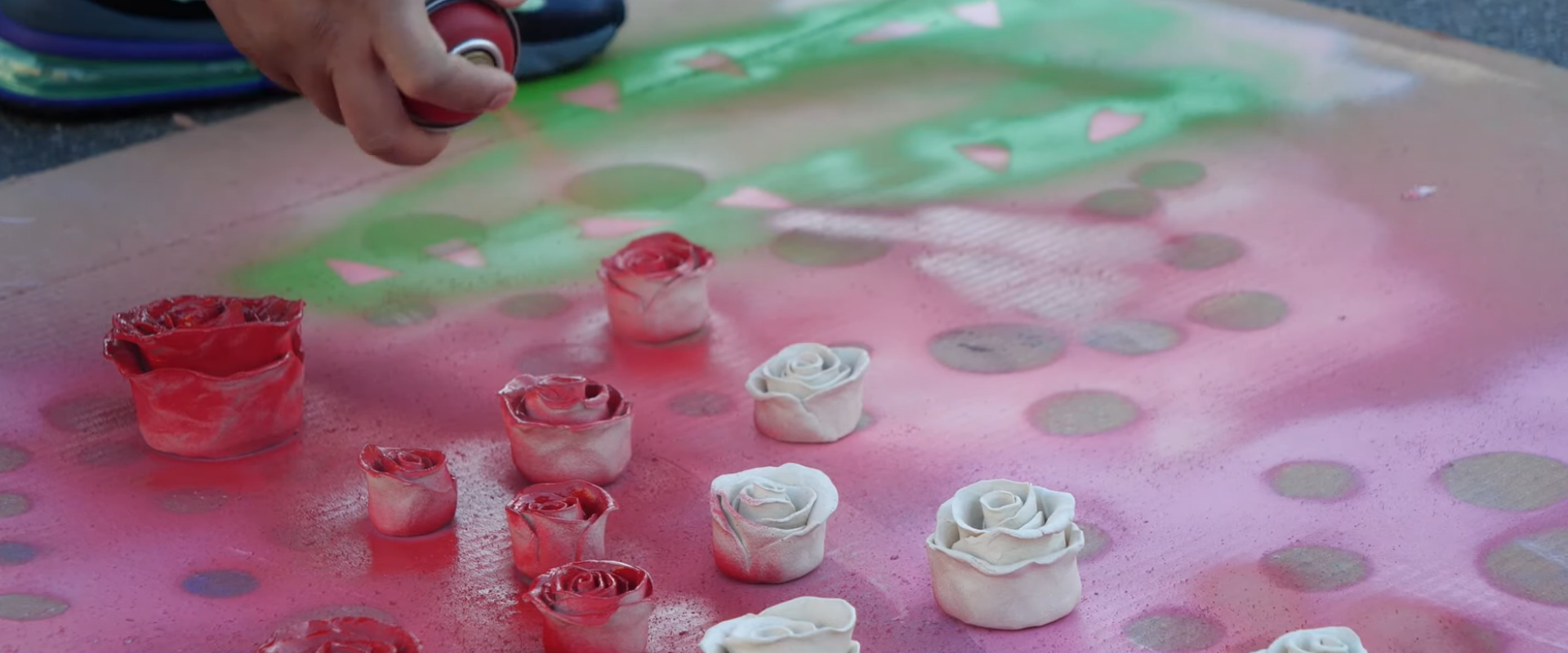 Still image of artist Patrick Martinez working on spray painting sculptural roses taken from Art Encounter studio visit educational video series available on Kleefeld Contemporary YouTube