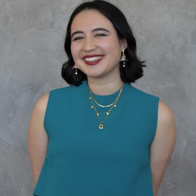Light skinned female-presenting with short black hair and a teal outfit.