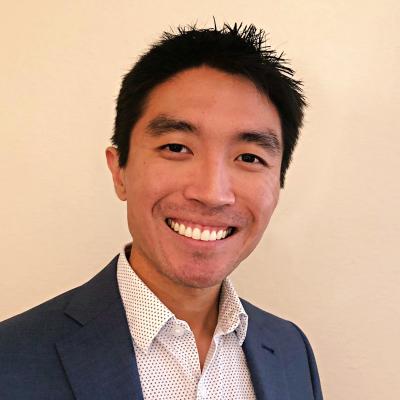 Daniel looks at the camera and smiles with his head slightly tilted