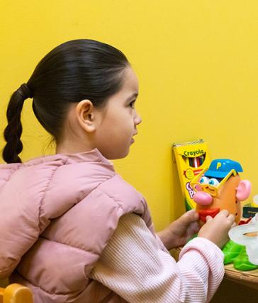 Young girl playing with Mr. Potato Head