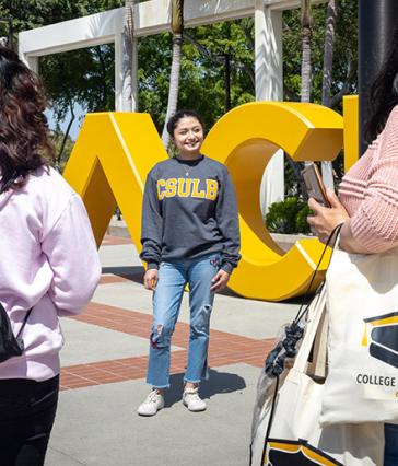 Student stands in front of BEACH sign